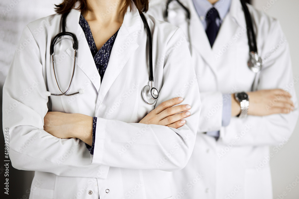 Group of modern doctors standing as a team with arms crossed in hospital office and ready to help patients. Medical help, insurance in health care, best disease treatment and medicine concept Group of modern doctors standing as a team with arms crossed in hospital office and ready to help patients. Medical help, insurance in health care, best disease treatment and medicine concept