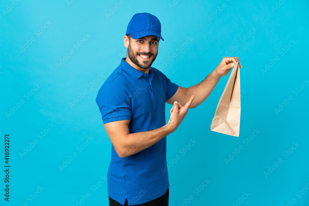 Delivery man with beard isolated on blue background and pointing it Delivery man with beard isolated on blue background and pointing it