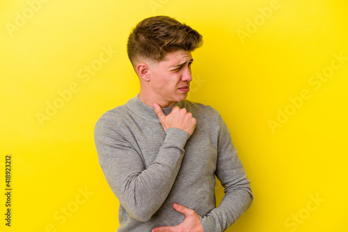 Young caucasian man isolated on yellow background suffers pain in throat due a virus or infection. © Asier