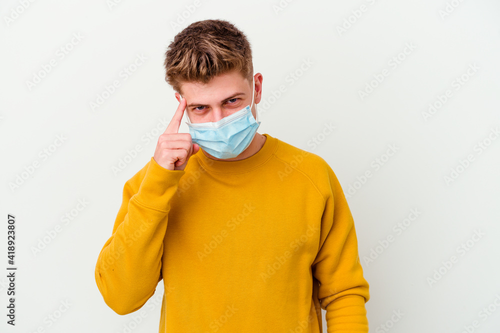 Young man wearing a mask for coronavirus isolated on white background pointing temple with finger, thinking, focused on a task. Young man wearing a mask for coronavirus isolated on white background pointing temple with finger, thinking, focused on a task.