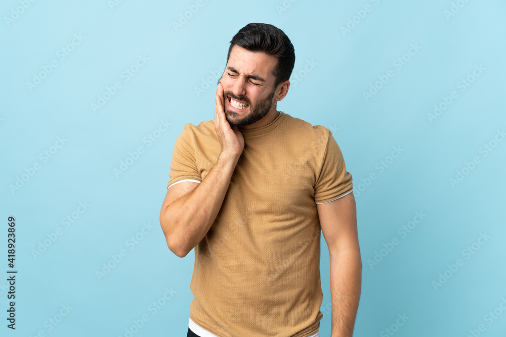 Young handsome man with beard over isolated background with toothache Young handsome man with beard over isolated background with toothache
