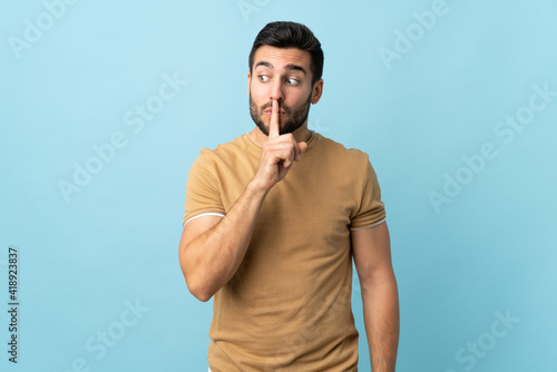 Young handsome man with beard over isolated background showing a sign of silence gesture putting finger in mouth