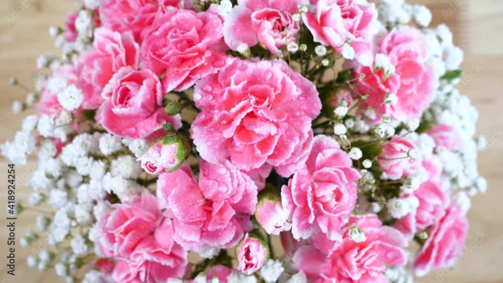 Panning shot of bouquet pink carnation spray flower with water drops on wooden table Panning shot of bouquet pink carnation spray flower with water drops on wooden table