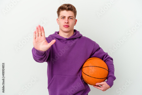 Young caucasian man playing basketball isolated background standing with outstretched hand showing stop sign, preventing you.