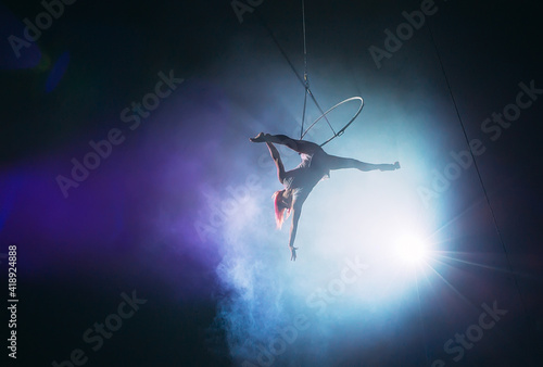 Aerial acrobat in the ring. A young girl performs the acrobatic elements in the air ring.