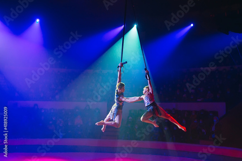 Circus actress acrobat performance. Two boys perform acrobatic elements in the air. photo