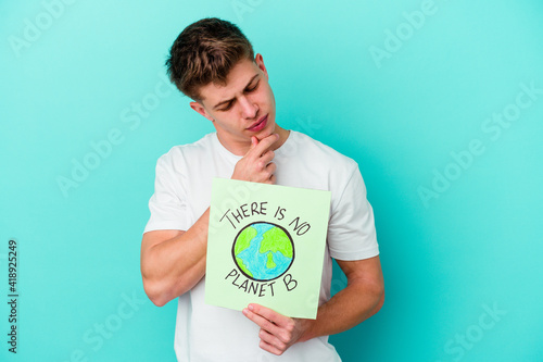 Young caucasian man holding a there is not planet b placard isolated on blue background