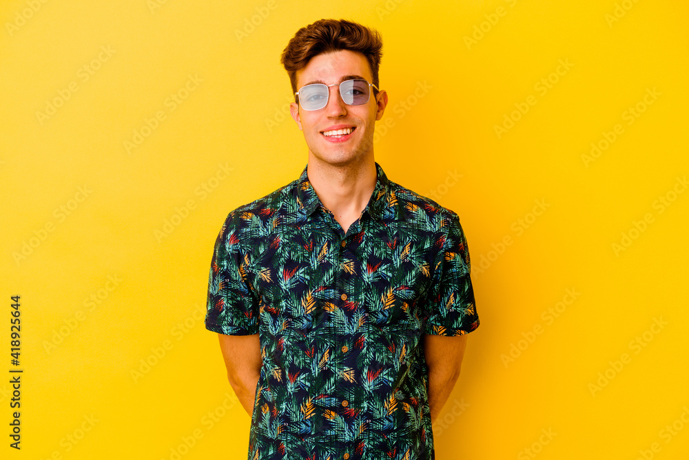 Young caucasian man wearing a Hawaiian shirt isolated on yellow background happy, smiling and cheerful. Young caucasian man wearing a Hawaiian shirt isolated on yellow background happy, smiling and cheerful.