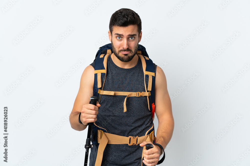 Young mountaineer man with a big backpack and trekking poles isolated on white background sad Young mountaineer man with a big backpack and trekking poles isolated on white background sad