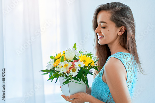 Beautiful caucasian joyful happy young smiling woman with decorative colorful bright fresh flower hat box at holiday spring women's day