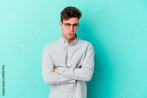 Young caucasian man isolated on blue background blows cheeks, has tired expression. Facial expression concept. © Asier