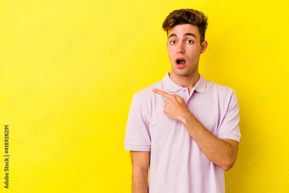 Young caucasian man isolated on yellow background pointing to the side Young caucasian man isolated on yellow background pointing to the side