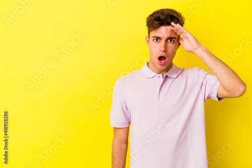 Young caucasian man isolated on yellow background shouts loud  keeps eyes opened and hands tense.