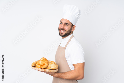 Obraz na plátně Male baker holding a table with several breads isolated on white background laug
