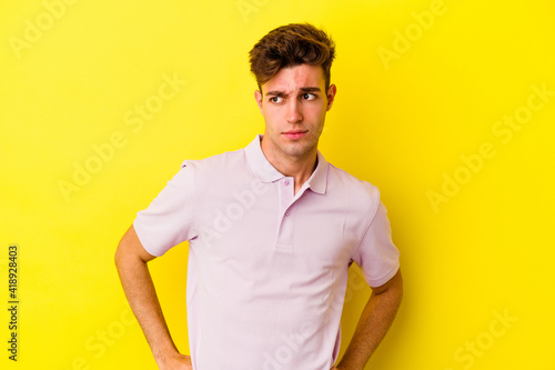 Young caucasian man isolated on yellow background confused, feels doubtful and unsure. © Asier
