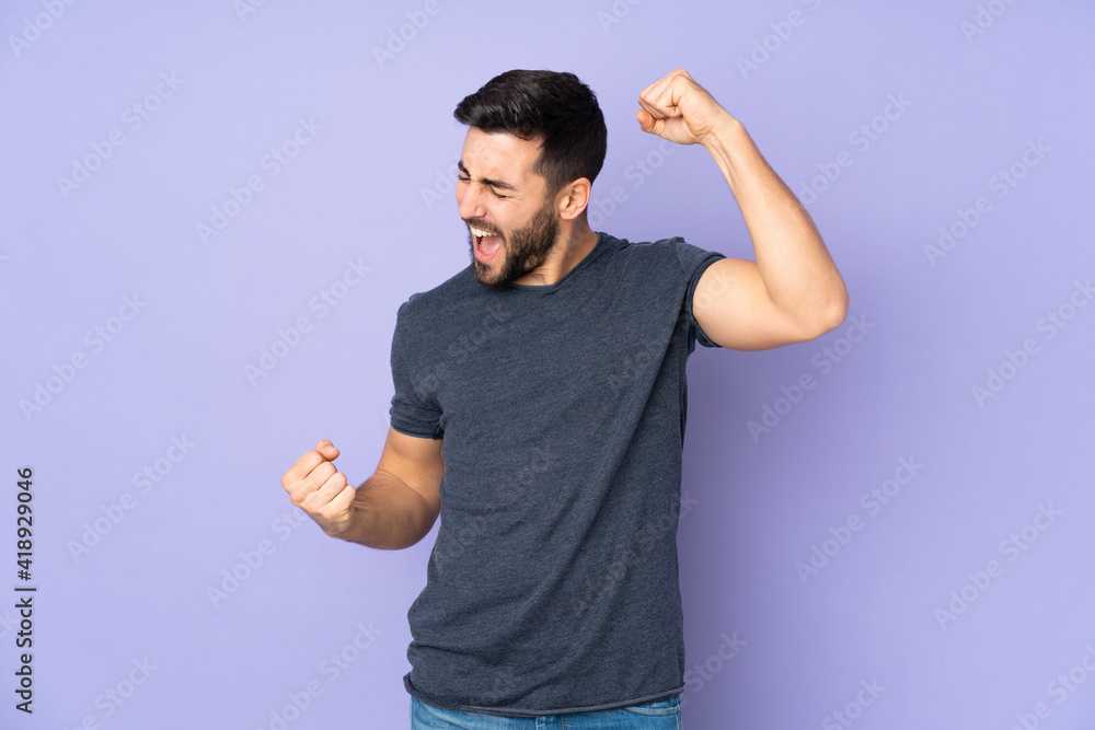Caucasian handsome man celebrating a victory over isolated purple background Caucasian handsome man celebrating a victory over isolated purple background