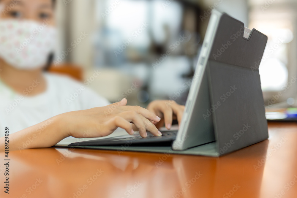 Young child student with protective mask hands typing on laptop. Young child student with protective mask hands typing on laptop.
