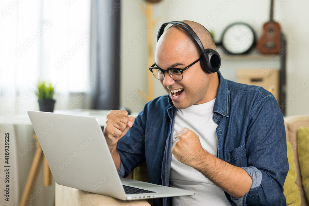 Young handsome asian man meeting and conferencing online keep social distancing talking with his business team online or study online course. He wearing headset. Young handsome asian man meeting and conferencing online keep social distancing talking with his business team online or study online course. He wearing headset.