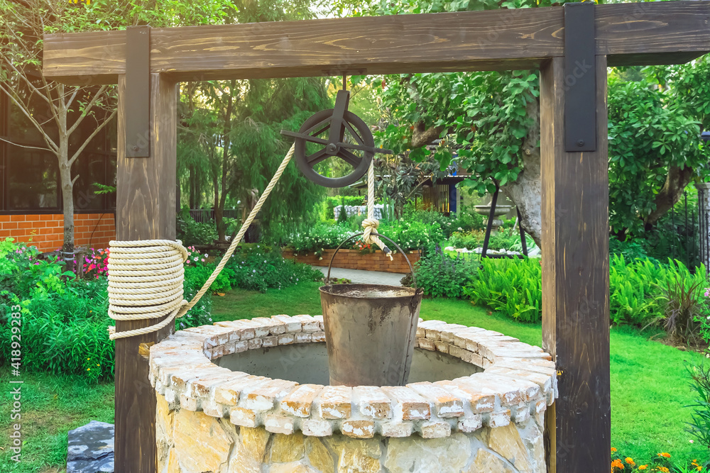Beautiful artesian well made by stones and wheel pulley with metal