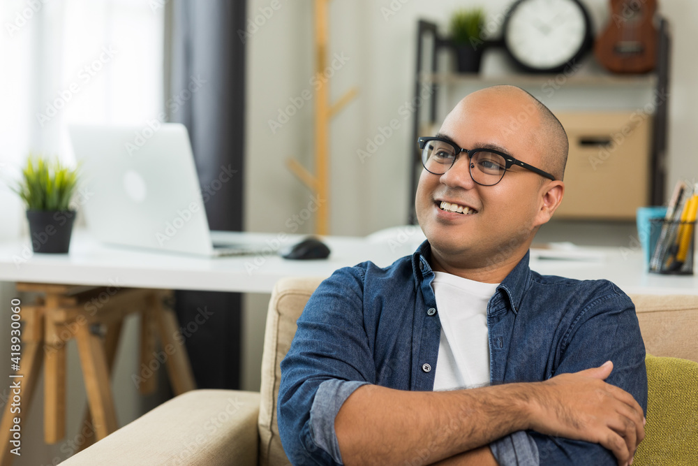 Young asian man Sit and relax in the living room on the sofa. He rested from work and smile. Young asian man Sit and relax in the living room on the sofa. He rested from work and smile.