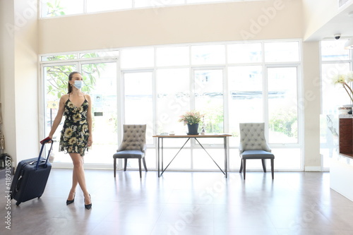 A Young woman wearing medical masks with baggage ,  while waiting to check in the hotel, New normal travel lifestyle concept © sittinan