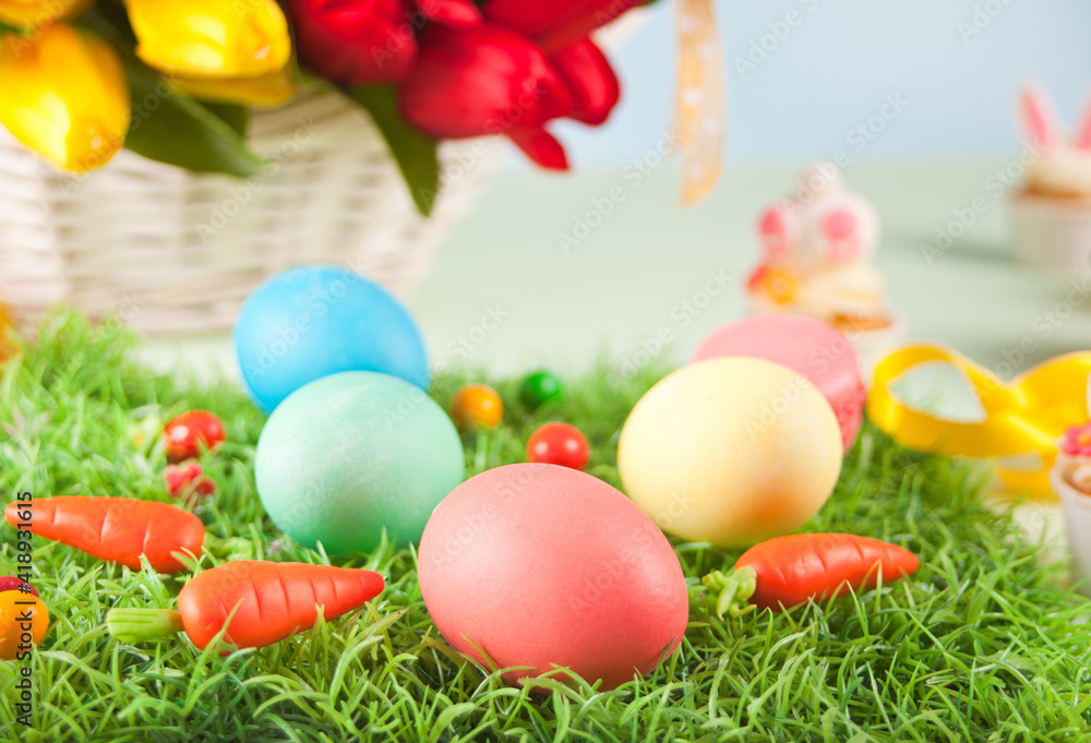 Three decorated easter eggs in the grass with flowers tulips on the background