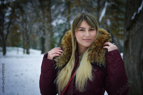 Beautiful blonde girl walking in the park on snowy winters day.