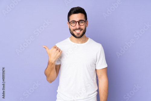 Caucasian handsome man over isolated background pointing to the side to present a product