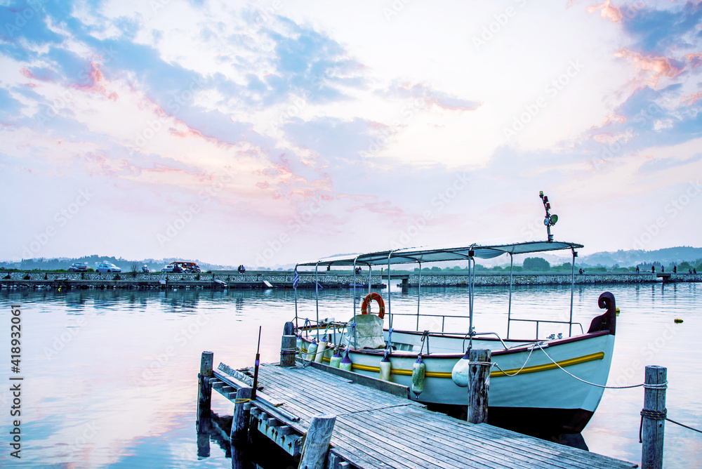 Breathtaking upbeat inspirational landscape with a boat on a lake near pier at dawn near Vlacherna Monastery on the Kanoni peninsula in Kerkyra, Corfu, Greece. amazing places.