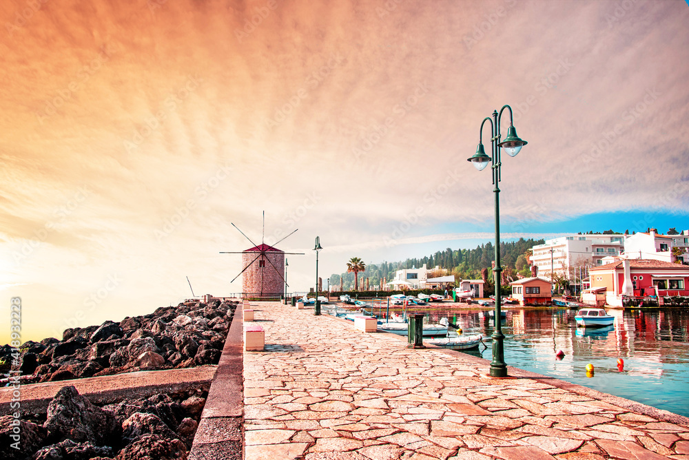 Charming seafront view with stones, lanterns and old windmill on the coast of the Mon Repose area in Kerkira, capital of Corfu, Greece at sunrise. Amazing places. Popular tourist atraction.