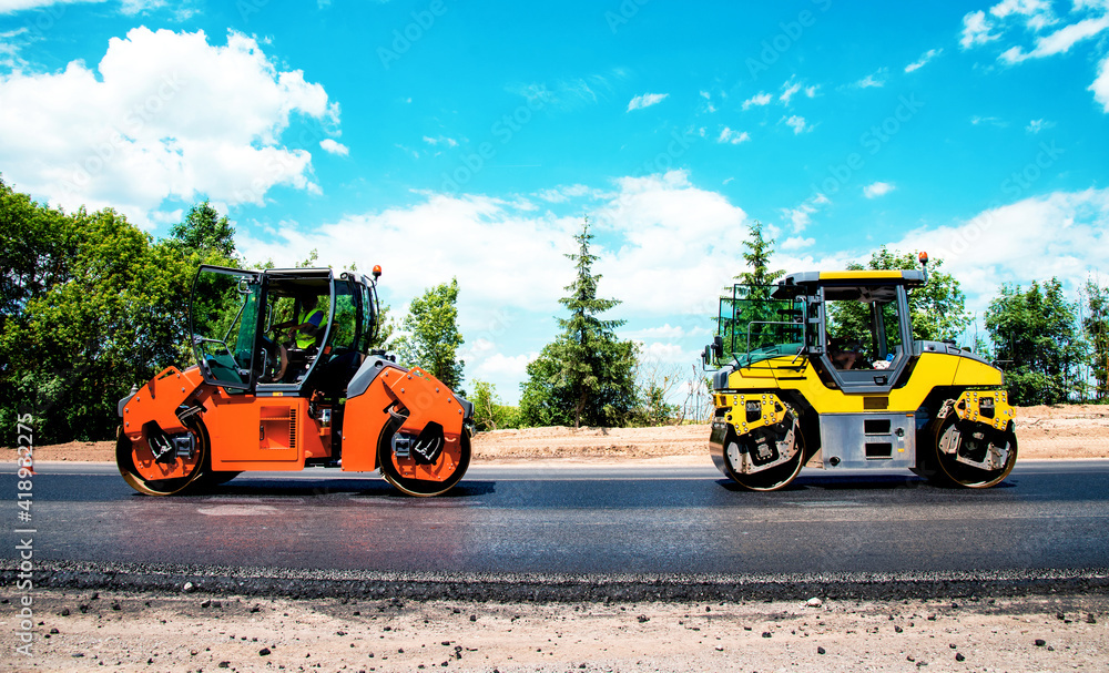 industrial landscape with rollers that rolls a new asphalt in the roadway. Repair, complicated transport movement.