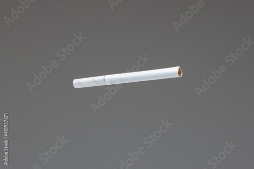 Single white unlit cigarette close up macro studio shot isolated on gray background shallow depth of field