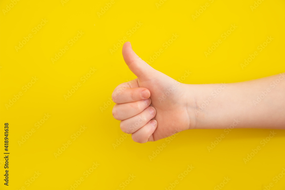 Girl showing thumbs up against yellow background