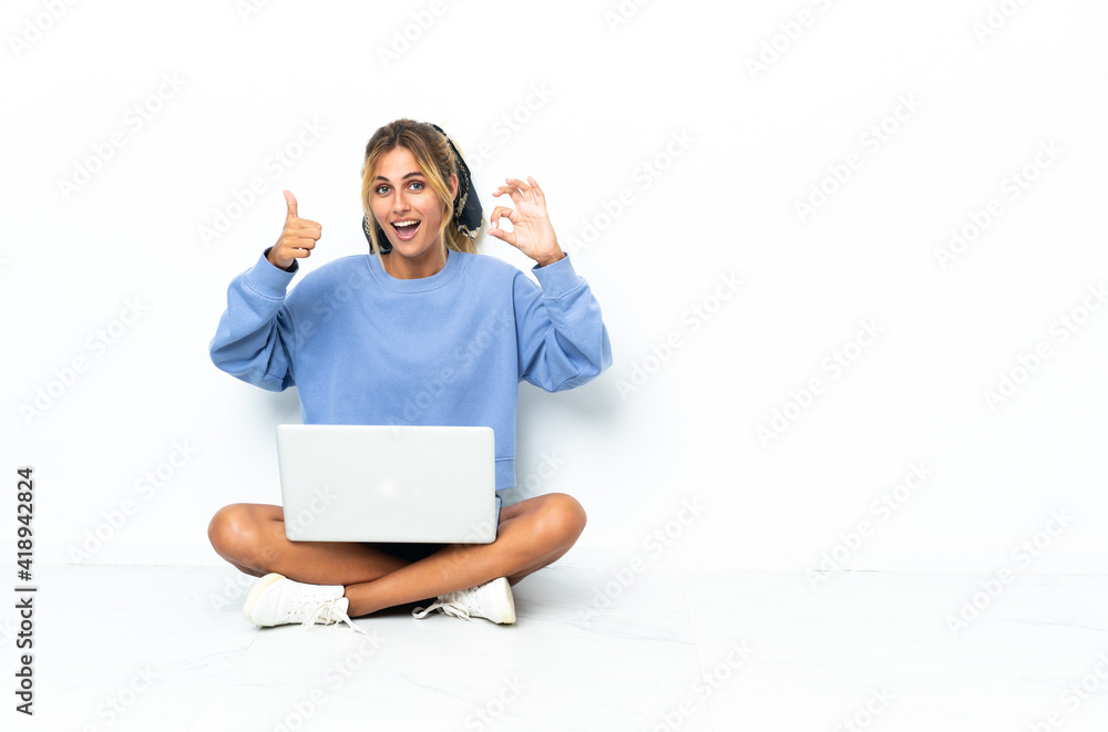 Young blonde Uruguayan girl with the laptop isolated on white background showing ok sign and thumb up gesture Young blonde Uruguayan girl with the laptop isolated on white background showing ok sign and thumb up gesture