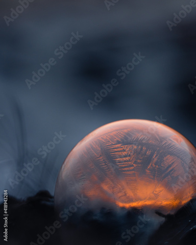 Frozen soap bubble with beautiful light and color on a wooden structure