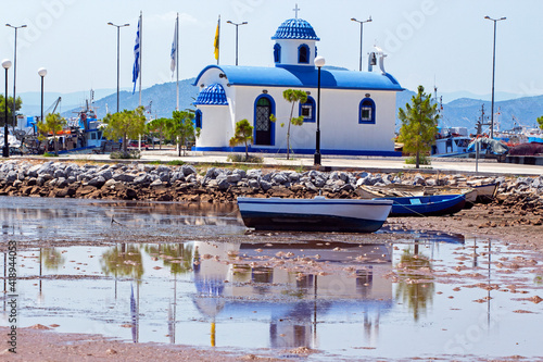 Fishing boats and the chapel of Agios Nikolaos in the port of Nea Artaki in Euboea, Greece. Sunny summer day , during low tide
