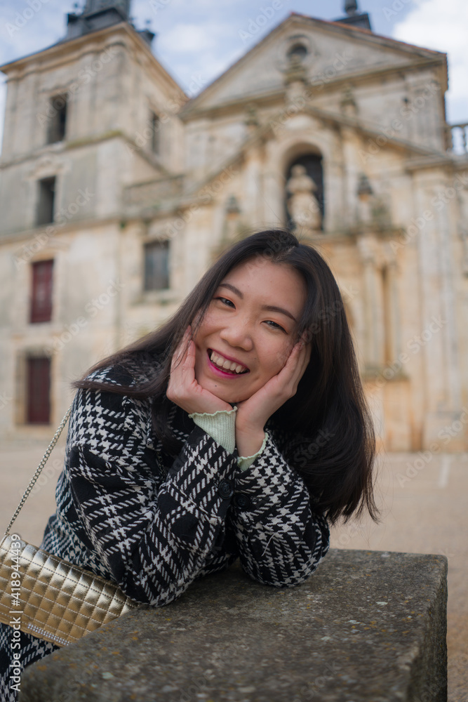 Asian woman enjoying holidays as tourist in Europe - lifestyle portrait of young happy and beautiful Chinese girl in autumn coat touring the city relaxed and cheerful