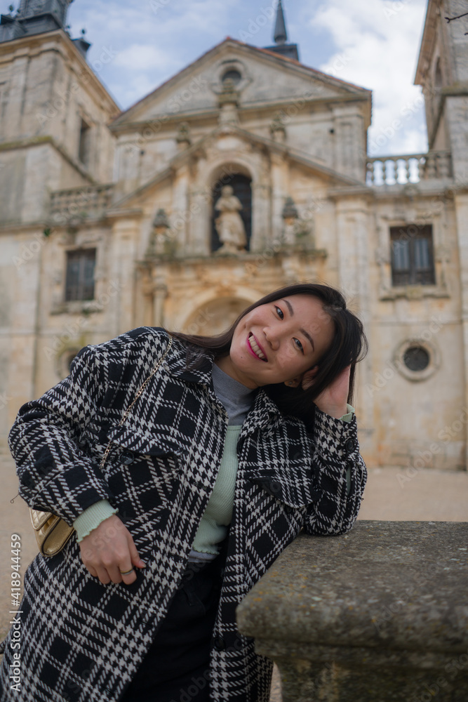 Asian woman enjoying holidays as tourist in Europe - lifestyle portrait of young happy and beautiful Japanese girl in autumn coat touring the city relaxed and cheerful
