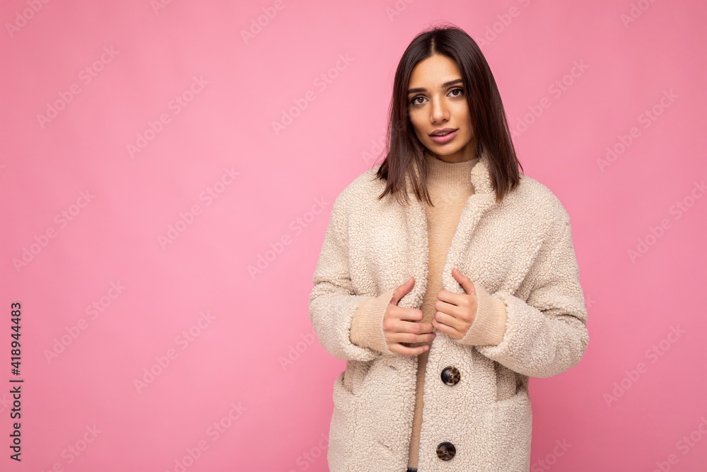 European beautiful young brunette woman wearing stylish beaige warm coat isolated over pink background with copy space. Fashion concept European beautiful young brunette woman wearing stylish beaige warm coat isolated over pink background with copy space. Fashion concept