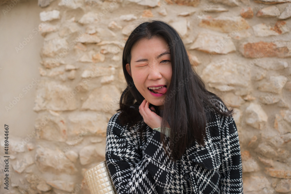 natural portrait of young happy and beautiful Asian Chinese woman in chic Autumn coat smiling cheerful posing playful bringing positive vibes outdoors on stone wall background natural portrait of young happy and beautiful Asian Chinese woman in chic Autumn coat smiling cheerful posing playful bringing positive vibes outdoors on stone wall background