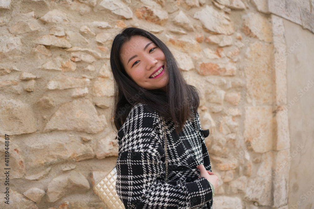 natural portrait of young happy and beautiful Asian Korean woman in chic Autumn coat smiling cheerful posing playful bringing positive vibes outdoors on stone wall background natural portrait of young happy and beautiful Asian Korean woman in chic Autumn coat smiling cheerful posing playful bringing positive vibes outdoors on stone wall background