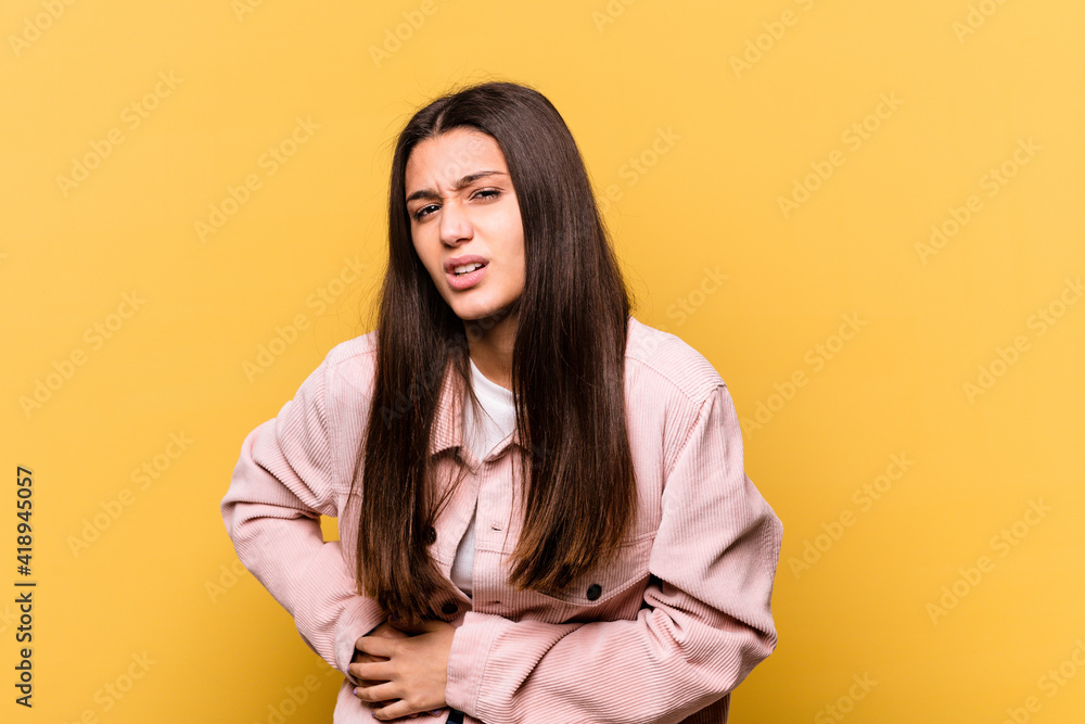 Young Indian woman isolated on yellow background having a liver pain, stomach ache. Young Indian woman isolated on yellow background having a liver pain, stomach ache.