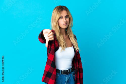 Young blonde Uruguayan woman over isolated background showing thumb down with negative expression