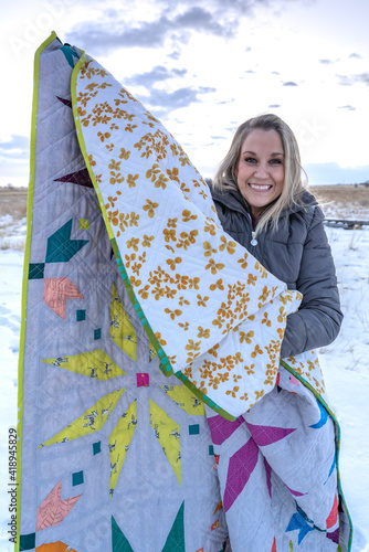 woman displaying brightly colored quilt photo