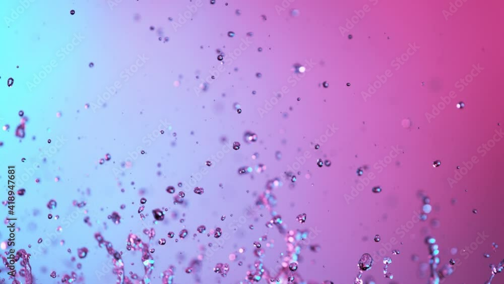Super slow motion of splashing water illuminated by neon lights. Filmed on high speed cinema camera, 1000 fps.