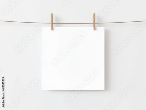 One blank square note paper card hanging with wooden clip or clothespin on rope string peg isolated on white backgroun. 3D illustration photo