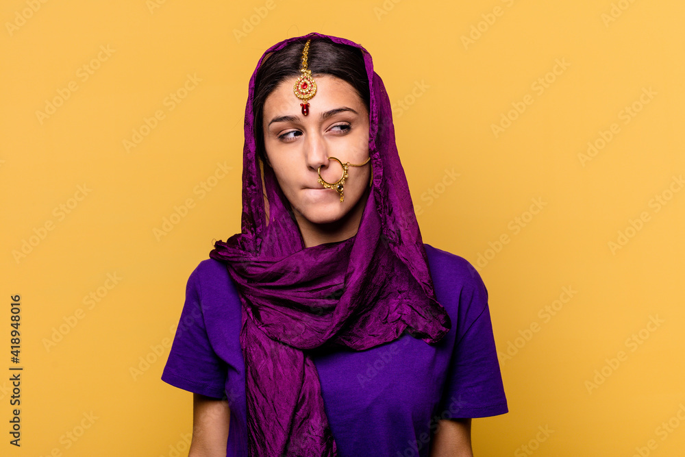 Young Indian woman wearing a traditional sari clothes isolated on yellow background confused, feels doubtful and unsure. Young Indian woman wearing a traditional sari clothes isolated on yellow background confused, feels doubtful and unsure.
