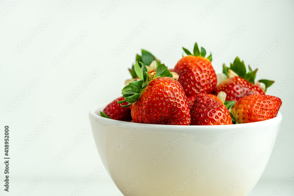 Close-up of red strawberries in a white bowl with white background. Close-up of red strawberries in a white bowl with white background.