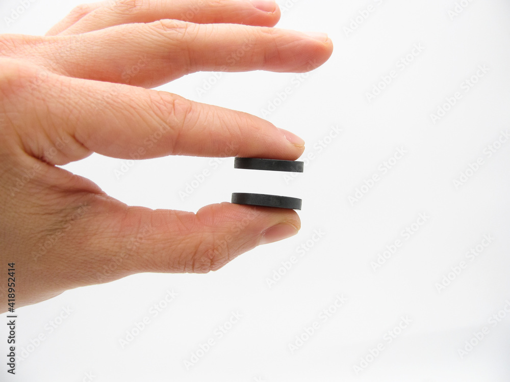 the two round little gray magnets between the two fingers of the hand do not touch each other the two round little gray magnets between the two fingers of the hand do not touch each other