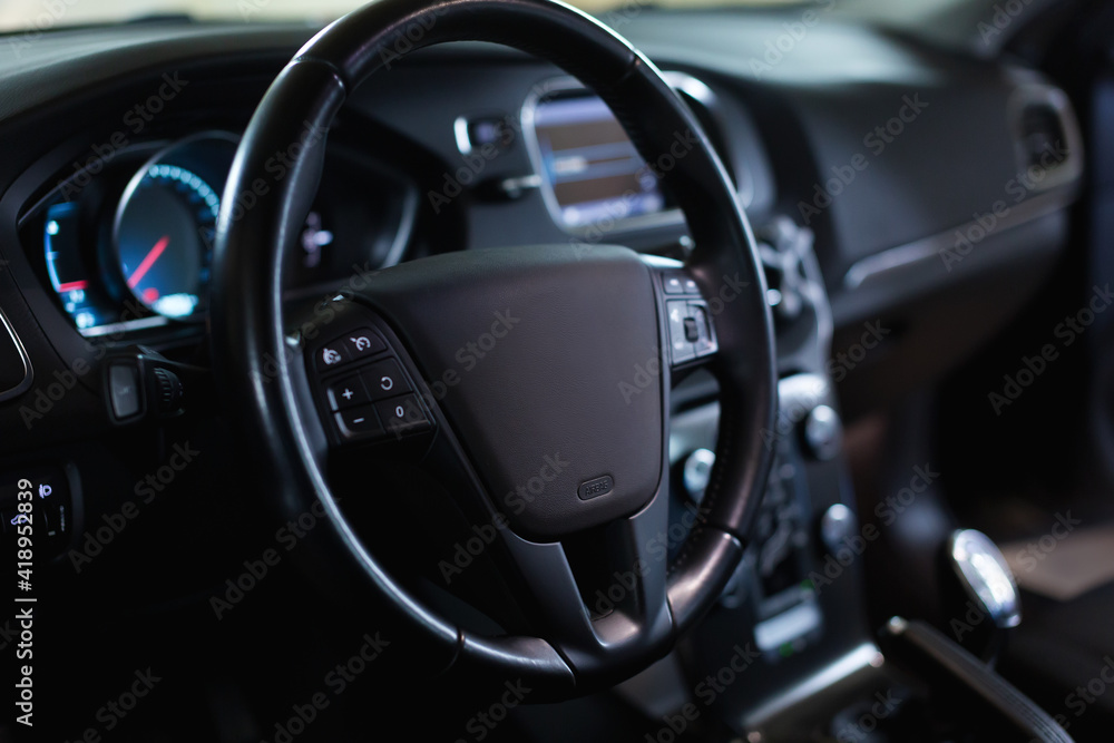 Dark luxury car Interior - steering wheel, shift lever and dashboard. Car interior luxury. Steering wheel, dashboard, climate control, speedometer, display.